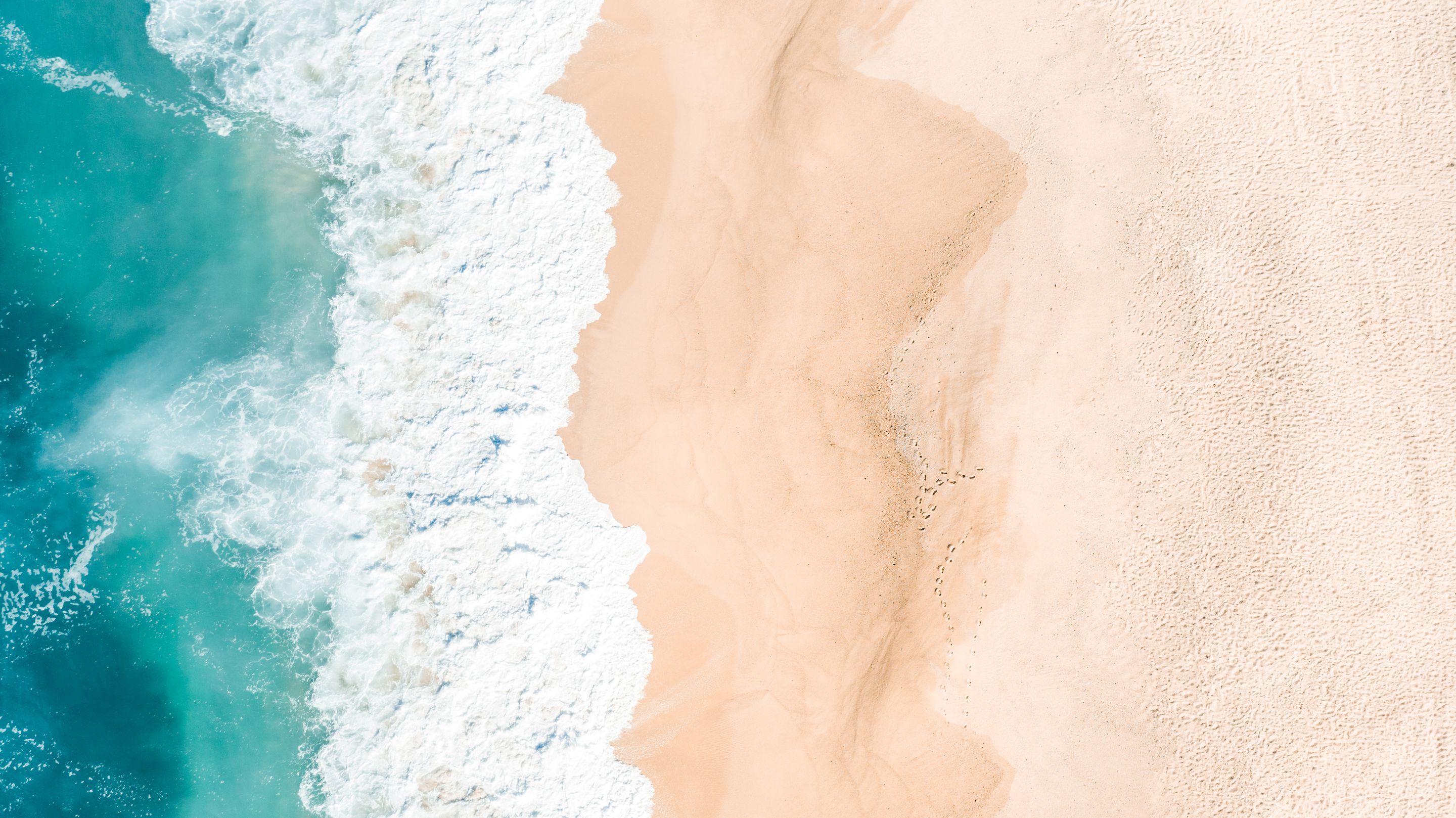 Aerial view of ocean waves washing onto a sandy beach